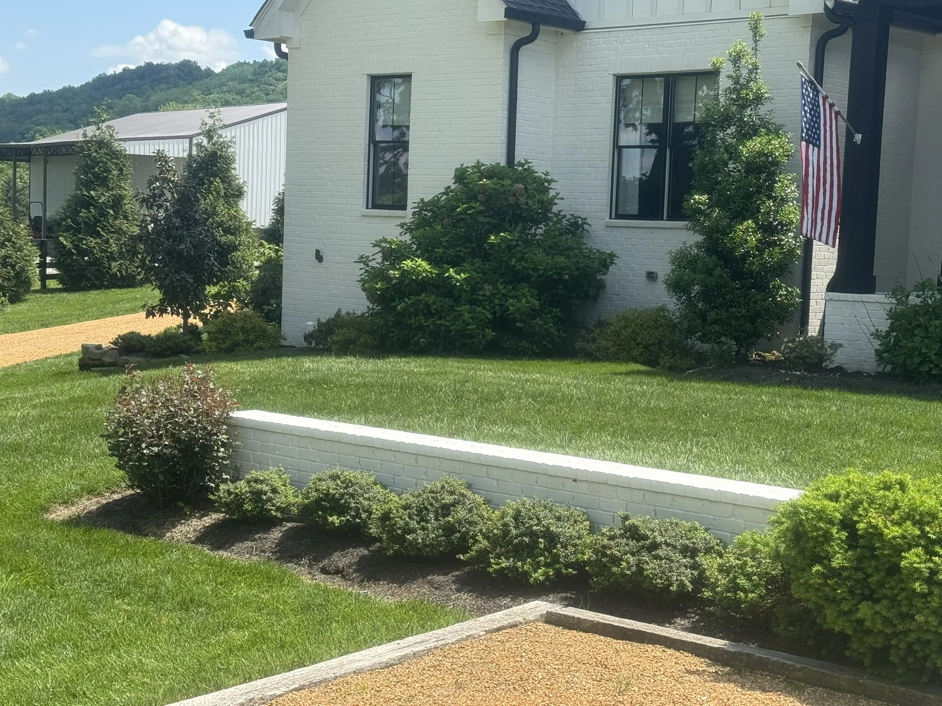 A Beautiful Fescue Lawn with a Retaining Wall and Some Ornamental Plants Around It — Mr. Lawn Care, Middle Tennessee lawn treatment